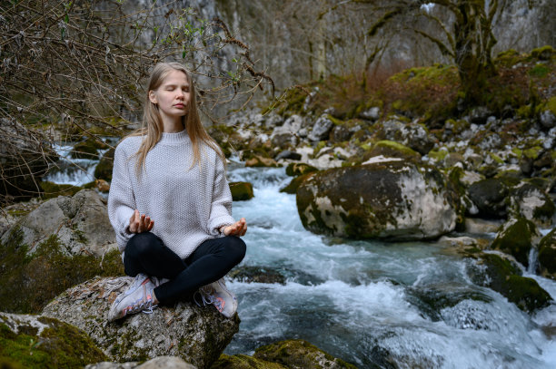 一个女孩坐在一棵树上，在阿布哈兹的山河附近冥想图片下载