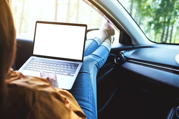 一个女人躺在车里，在笔记本电脑上用空白的桌面屏幕打字图片下载