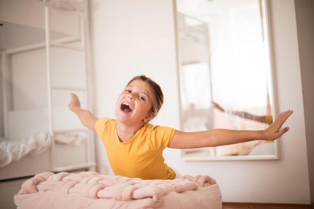 微笑的小女孩独自在卧室里玩。图片下载