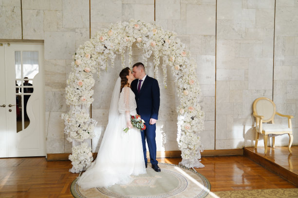 美丽而幸福的新娘和新郎在婚礼上花的拱门图片下载