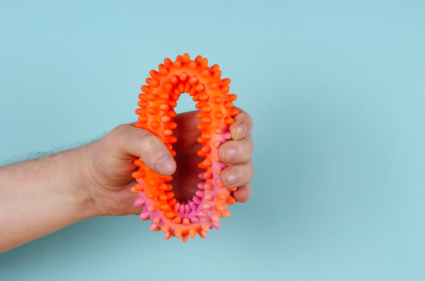 一只手抓着蓝色背景下的红色橡胶膨胀带。图片下载