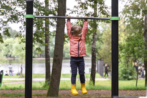 一个孩子挂在一个秋季公园的单杠上图片下载