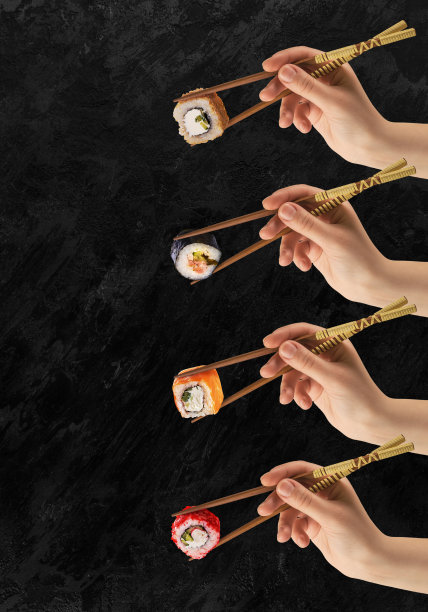女人的手拿着寿司卷。黑色背景。创造性的概念。图片下载