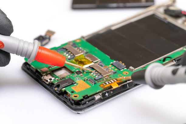 无线电工程大师修理手机的一部分，用数字万用表对其进行测量，大师的双手戴着黑手套可见。宏图片下载