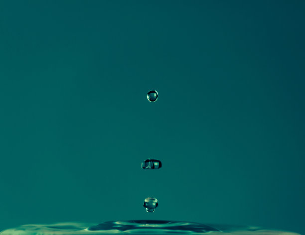 水滴落在蓝色的背景上溅起水花。宏观性质的照片图片下载