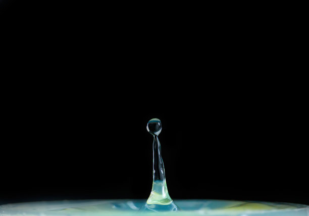 水滴落在黑色的背景上，溅起水花。宏观性质的照片图片下载