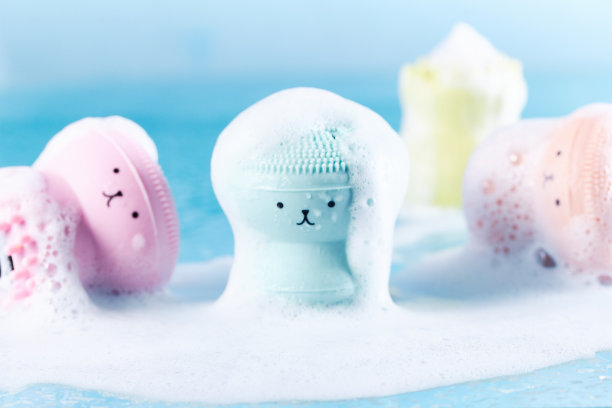 硅胶按摩刷洗涤与滑稽的脸在水覆盖泡沫。清洁清新，个人护理理念图片下载