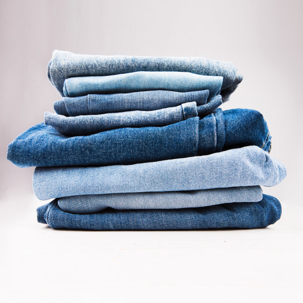 一堆不同深浅的蓝色牛仔布在白色的背景。洗衣房广告空白。图片下载