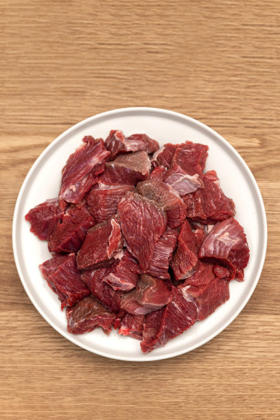 用大锅煮肉饭，真正的肉饭食谱。木质背景的肉饭配料。生肉放在木砧板上，切成块图片下载