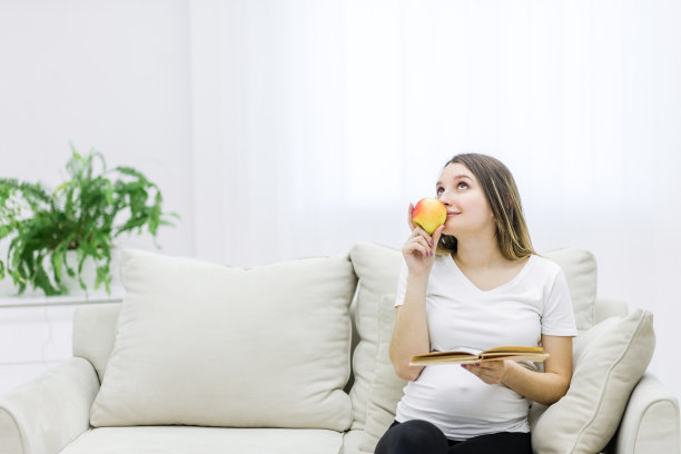 孕妇一边看书一边吃苹果的照片。图片下载
