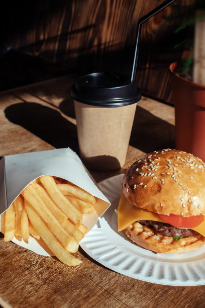 纸包装的汉堡，咖啡和炸薯条特写。快餐店里的食物。汉堡与肉，蔬菜，薯条和咖啡的微距照片。快餐食品集图片下载