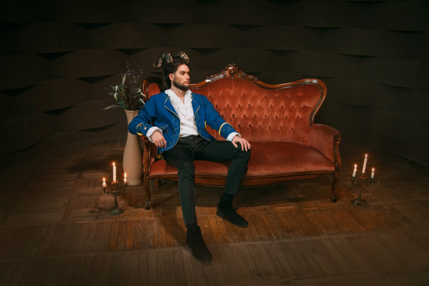 头戴羊角，坐在红色复古沙发上的自信男人图片下载