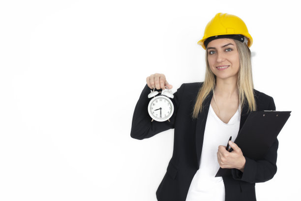 年轻的工程师的女人。手里拿着钟的女商人。他们的工作场所在病毒接种后开放。该开始工作了。业务和时间概念。图片下载