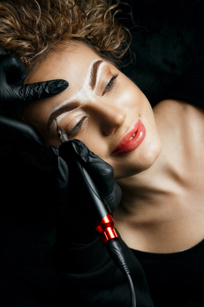 美容师在一个漂亮的女人额头纹身图片下载