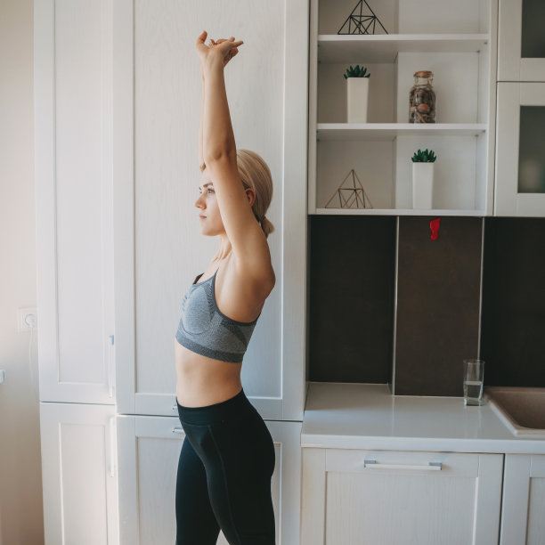 金发女人正伸展自己在厨房穿着运动服图片下载