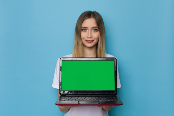 美丽的年轻女子拿着绿色屏幕的笔记本电脑。图片下载