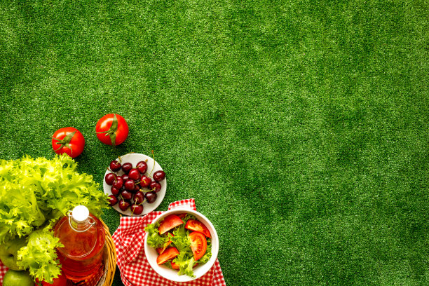 野餐设置在草地上，篮子和食物在红布上。俯视图片下载