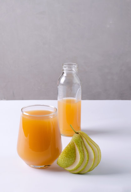 健康食品的概念。将果汁放在透明的玻璃上，在光的背景下，旁边切片的梨，选择性聚焦图片下载