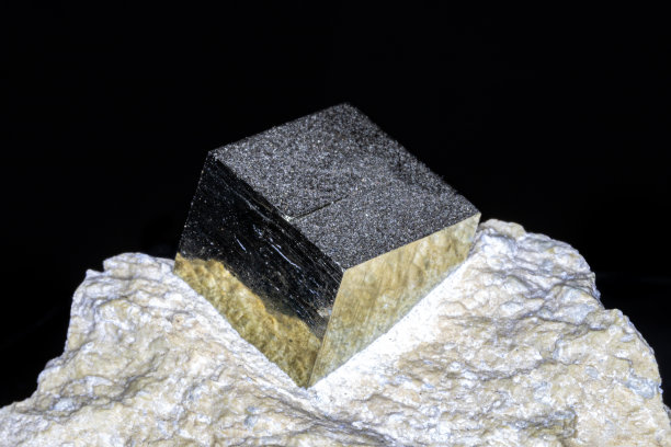 黄铁矿，天然立方体，嵌于宿主岩中。金属镜面光洁度。黑色背景。图片下载