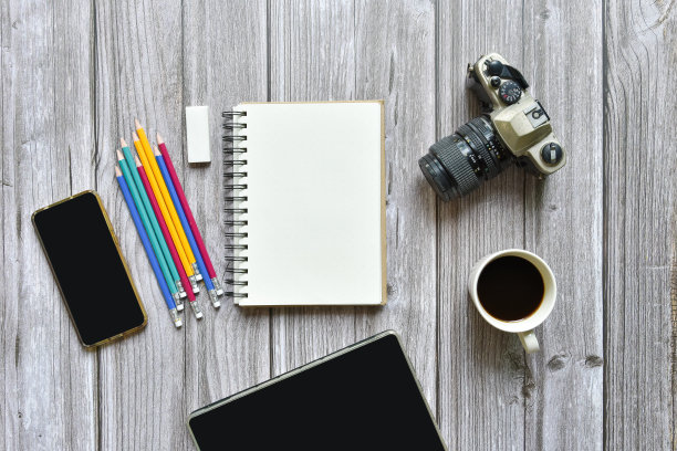 静物，商务或旅行者备忘录概念，顶部视图图像打开笔记本与复古相机咖啡彩色铅笔和平板与空白页上的老棕色木制背景，添加文本图片下载