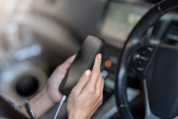 近距离的年轻女子用手机在车里。图片下载