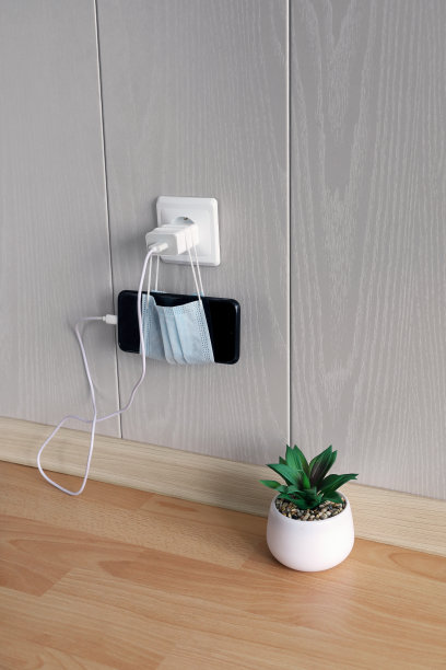 智能手机连接到电源插座，并将其放置在医用口罩的替代支架上图片下载