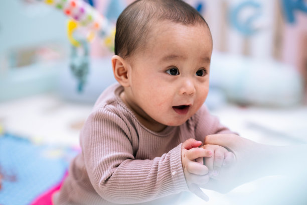 婴儿正在学着站在母亲旁边，帮助她扶着。库存图片图片下载