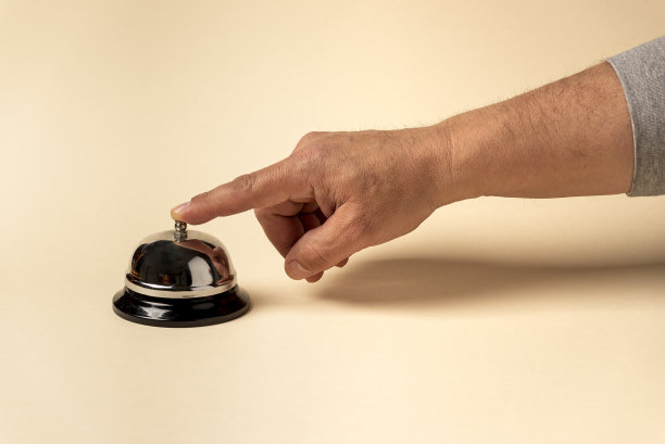 男性的手触摸银色的酒店钟孤立的米色背景与自由的文字空间图片下载