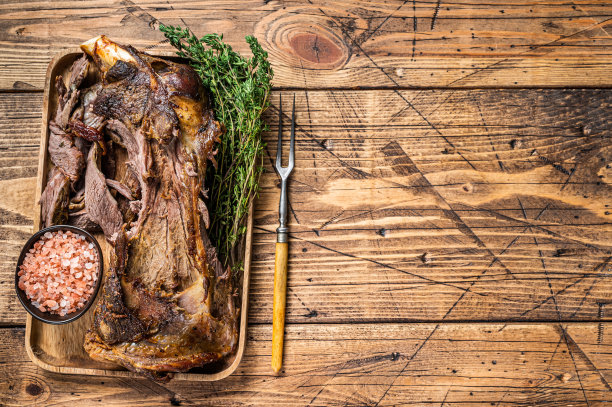 烤羊肉用肉叉在木托盘上切肩肉。木制背景。前视图。本空间图片下载