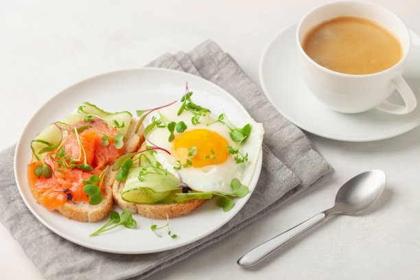 吐司配黄瓜、鲑鱼和鸡蛋放在桌子的盘子里图片下载