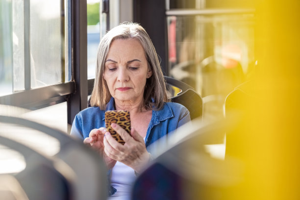 年长女性在公交车上使用手机图片下载