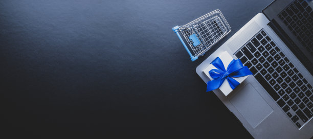 网上购物的背景。笔记本电脑，购物车和白色礼物与蓝色丝带在黑色。网上购物，网上商店的概念。网站零售业务。图片下载