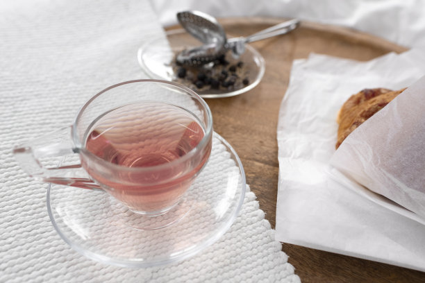 玻璃茶杯里放着新鲜的羊角面包和干香草图片下载