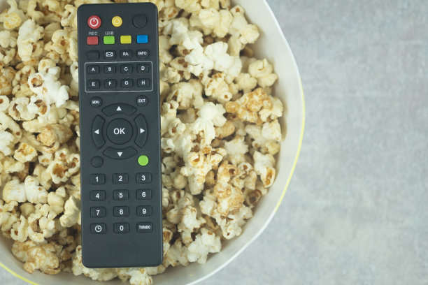 电视遥控器在碗爆米花，俯视图与文字空间。在家休息和放松的概念图片下载