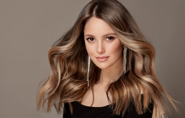 年轻，棕色头发美丽的模特，卷曲，浓密，染过的长发。优秀的头发。美发艺术与染发。图片下载