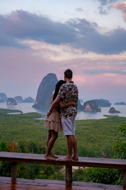 一对男女中年看日出在攀佳湾泰国，攀佳湾的观点，夫妇看日出在游泳池的边缘，无限池看泰国攀佳湾图片下载