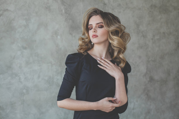 有魅力的女人化妆和卷发在灰色的背景图片下载