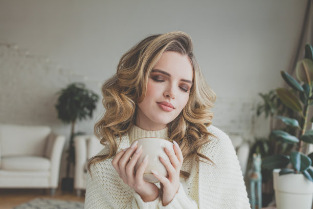 快乐的年轻女子在家里享受咖啡图片下载