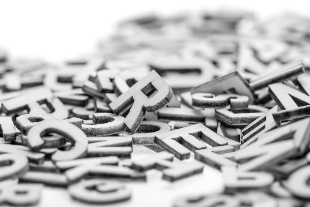 用激光切割机从薄胶合板上剪下的小木字，随机地堆在白色的背景上。黑与白的照片。图片下载