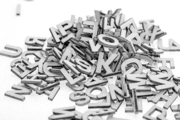 用激光切割机从薄胶合板上剪下的小木字，随机地堆在白色的背景上。黑与白的照片。图片下载