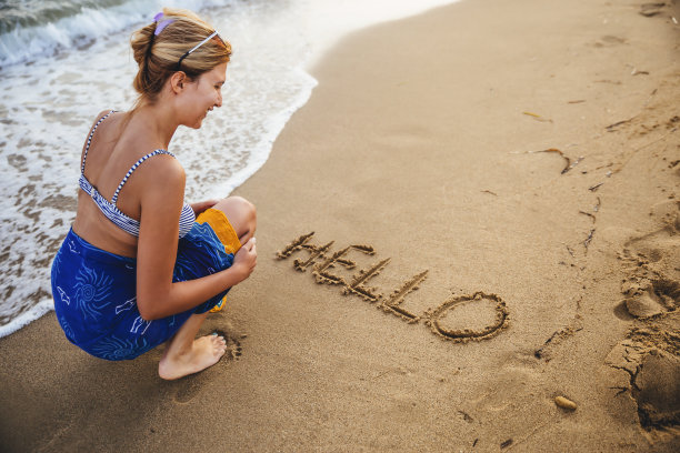 女人在沙滩上手写“你好”图片下载