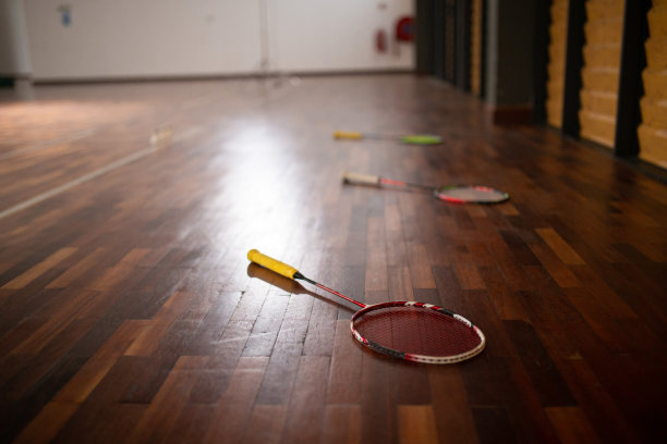 羽毛球场前地板上的羽毛球拍图片下载