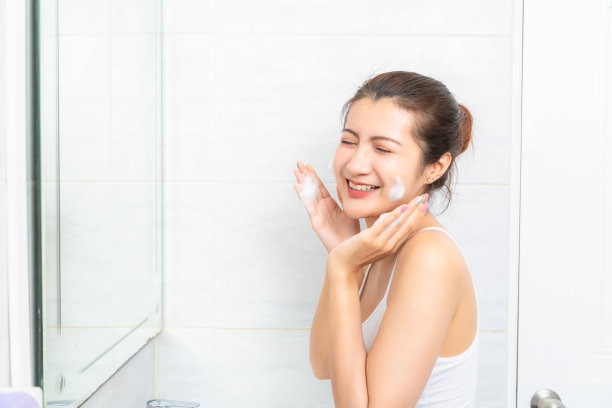 年轻的美女在浴室里洗脸。图片下载