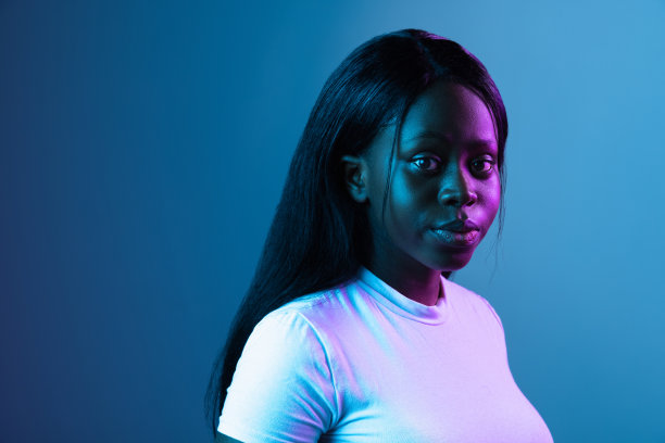 一个年轻的非洲美丽的女孩孤立在混合霓虹灯的黑暗背景。图片下载