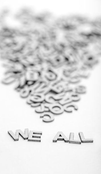 短语“我们所有人”是由小木头字母和随机字母堆在白色背景上。一个抽象的想法，将被证明在激励的话。黑与白的照片。图片下载