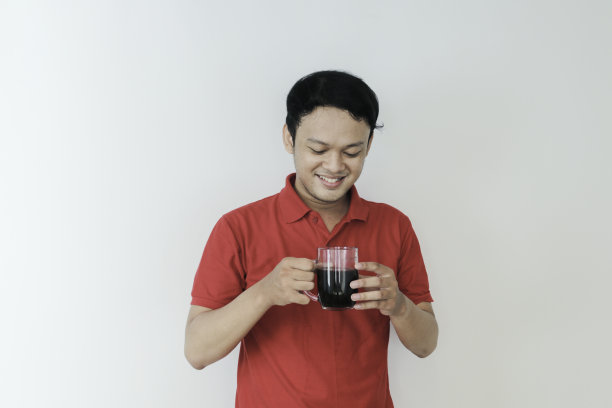 年轻的亚洲人拿着一杯咖啡站在孤立的白色背景高兴与大微笑。图片下载