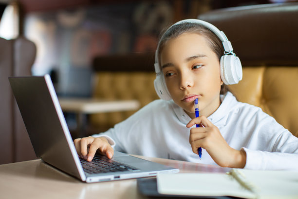 一张十岁女孩在家做作业的照片，她坐在笔记本电脑的屏幕前。女孩与老师在线视频通话图片下载