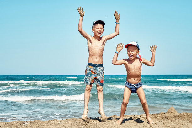 有趣快乐的小弟弟们在沙滩上跳向大海图片下载