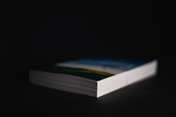 黑暗的桌面上孤零零地放着一本书。这本新小说还没读。51、模糊了书的封面，集中了书的边缘，读书使人概念充实。图片下载