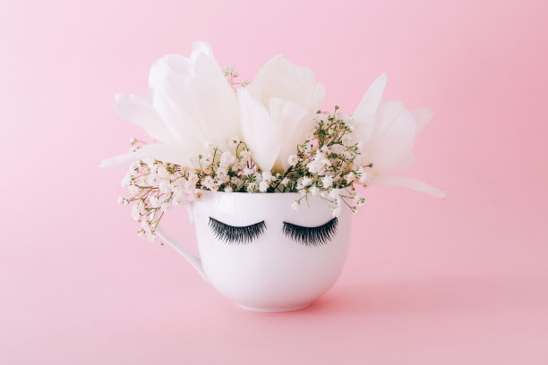 创意白色花杯与长睫毛在粉红色的背景。图片下载